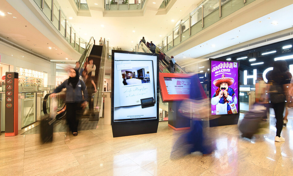 lightboxes in a mall, with a moderate density of people walking around